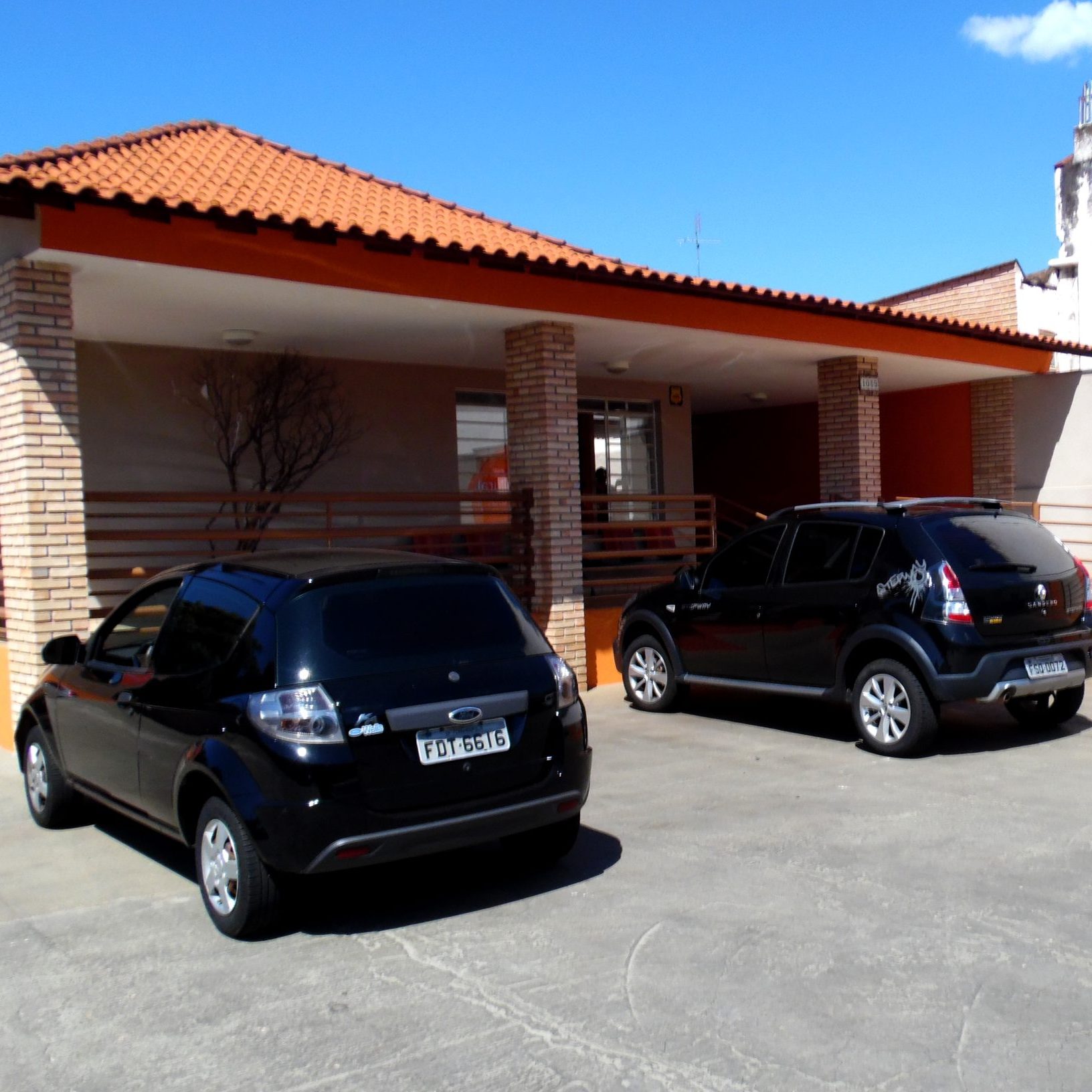 Um estacionamento na fachada da escola de idiomas, com dois carros pretos estacionados.
